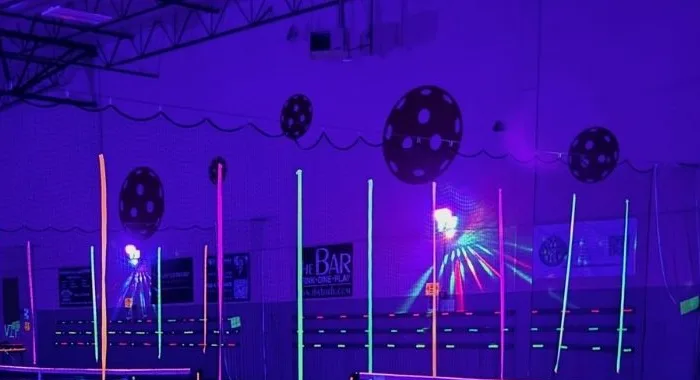 The arena under blacklights during a Vegas Indoor Pickleball glow night
